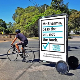 Man on Bicycle pulling a sign